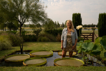 Landscaping and water gardens. Portrait of a woman in her 60s inside a pond growing aquatic plants...