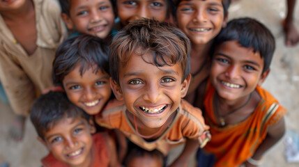Group of Indian villager boys in a tight group, happy and smiling, looking up. - obrazy, fototapety, plakaty
