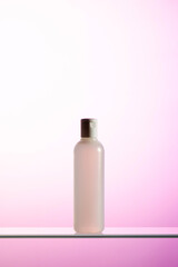 A plastic bottle with liquid cosmetics and tonic stands on a glass shelf 