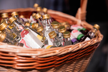 Assorted Miniature Bottles of Liquor in a Woven Basket at a Bar