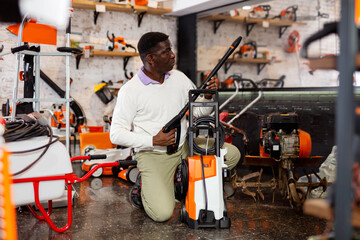 African-american man choosing compact high-pressure washer in gardening tools store.