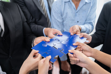 Multiethnic business people holding jigsaw pieces and merge them together as effective solution...
