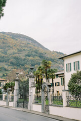 Expensive villas behind wrought-iron fences at the foot of the mountains. Lake Como, Italy