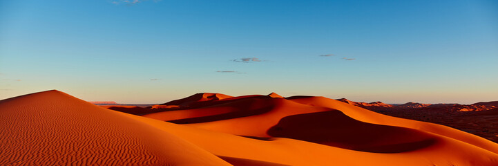 Sunset in the Sahara desert. The sun illuminates the dunes red. Without any human traces. Merzouga, Morocco