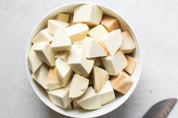 Overhead view of Nigerian white yam cubes in a white ceramic bowl, African yam cut into large cubes for cooking