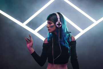 A female DJ with blue hair mixing music at a club, smoke and neon stage triangles in the background.
