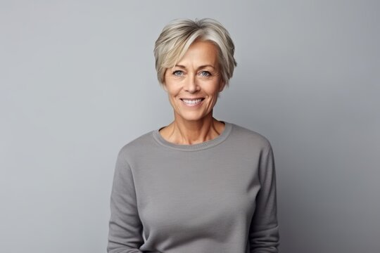 Portrait of a happy mature woman smiling at the camera over grey background