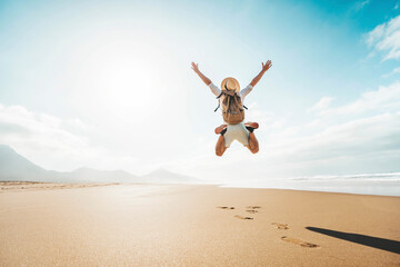 Happy traveler with hands up jumping at the beach - Delightful man enjoying success and freedom outdoors - Wanderlust, wellbeing, travel and summertime holidays concept - obrazy, fototapety, plakaty