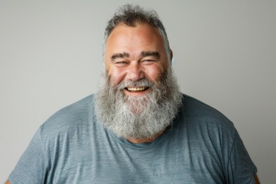 Full body photograph of an overweight middle aged man with a beard smiling and making eye contact with the camera placed against a white background