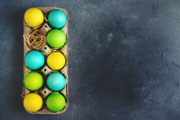 Fototapeta na wymiar Bright colorful easter eggs in egg carton on grey background. Top view, Copy space