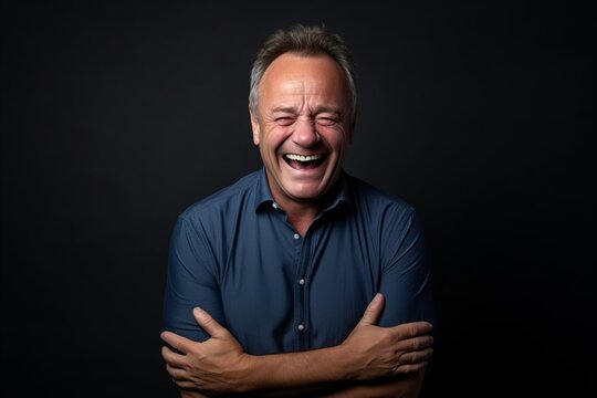 Portrait of a senior man laughing, isolated on black background.