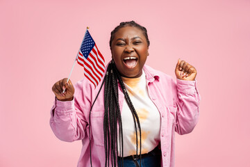 Portrait happy stylish African American woman, supporter holding USA flag, waiting for presidential...