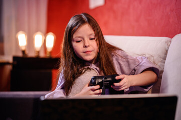 A young girl reacts while gaming, her face showing the emotional highs and lows that come with the challenges of navigating through digital play