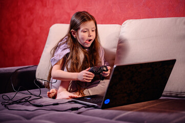 A young girl is deeply focused while playing a video game, her expression a blend of concentration...