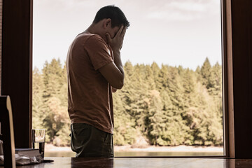 Frustrated Man stands by a window and puts his hand to his face, person  Grieving Feeling...