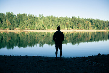 Young Thoughtful Man Standing Next To a Tranquil Lake Enjoying Peace Quiet Time in Nature 