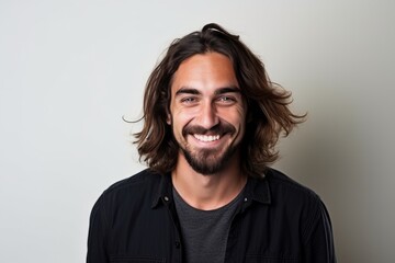 Portrait of a handsome man with long hair smiling at the camera - obrazy, fototapety, plakaty