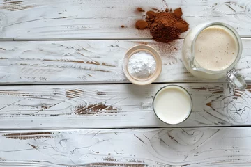 Fotobehang Top view of white wooden table with protein shake milk jug and powder on a glass © VolumeThings