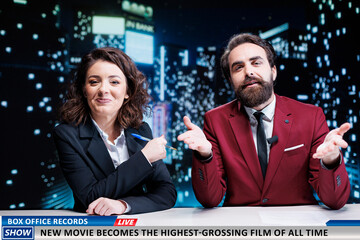 Newscasters team reveal new movie premiere breaking box office records, broadcasting live on...