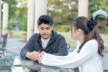 A young Japanese male and female couple in their 20s discussing in a green park in Nagoya City, Aichi Prefecture 愛知県名古屋市の緑あふれる公園で話し合う若い２０代の日本人男女カップル