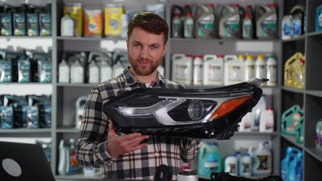 Auto parts seller holds automotive headlight in auto parts store