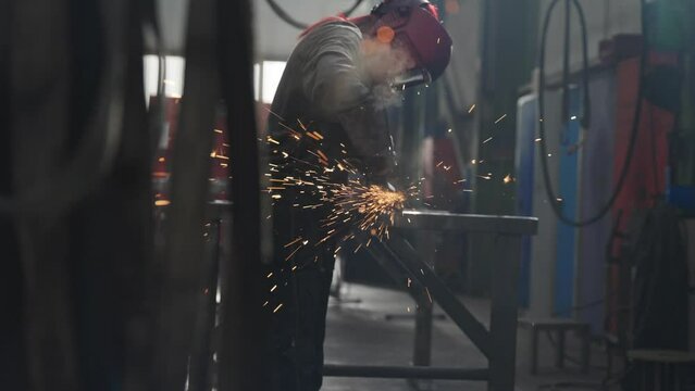 Arbeiterin schleift den Stahl mit dem Winkelschelifer / Flex ab und bereitet ihn für den weiteren Arbeitsvorgang für die Industrie vor.