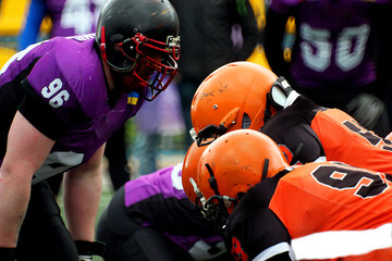 American football players in orange uniforms against players in purple uniforms	
