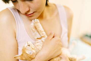 Young Woman Holding a Playful Orange Tabby Kitten