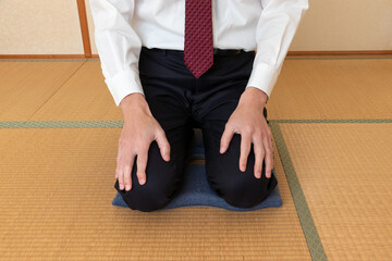上着を脱いで正座する白いワイシャツ姿の男性