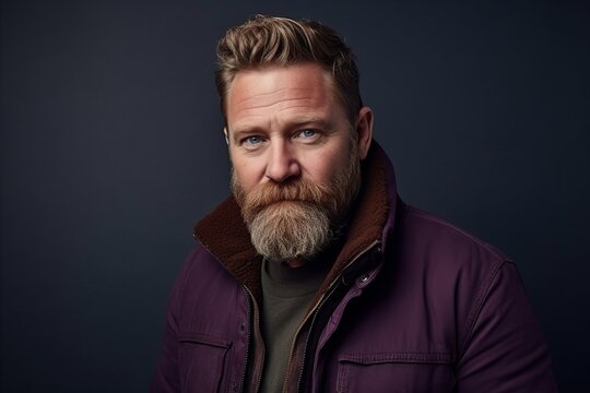 Portrait of a handsome mature man with long beard and mustache wearing a purple jacket. Men's beauty, fashion.