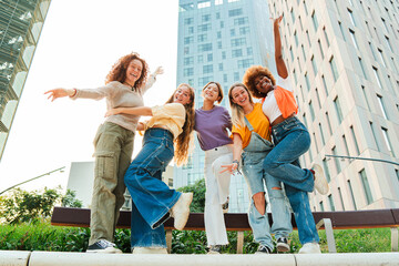 Group of playful female friends having fun on a social meeting. Young friendly women enjoying the freedom dancing an laughing together at weekend. Multiracial adult girls celebrating their friendship