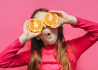 Little cute funny girl using grapefruit instead of eyes, having fun and fooling around in the...