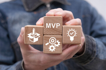 Man holding wooden cubes sees abbreviation: MVP. Minimum Viable Product ( MVP ) Business concept...