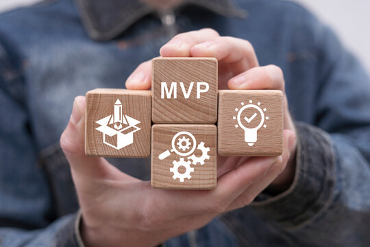 Man holding wooden cubes sees abbreviation: MVP. Minimum Viable Product ( MVP ) Business concept for lean startup. Life cycle of product development. Analysis and market validation.