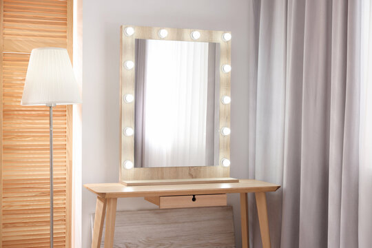 Beautiful mirror with light bulbs and lamp in makeup room