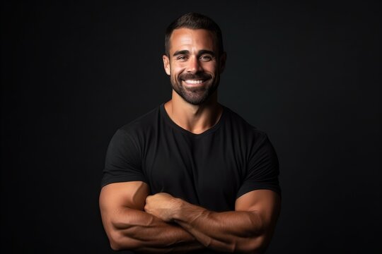 Portrait of a handsome man smiling with arms crossed on black background