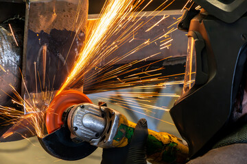Worker grinding steel structure using an electric grinder