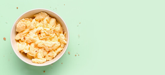Bowl of delicious scrambled eggs on turquoise background with space for text