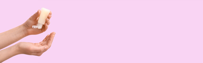 Woman applying sanitizer on her hands against pink background with space for text