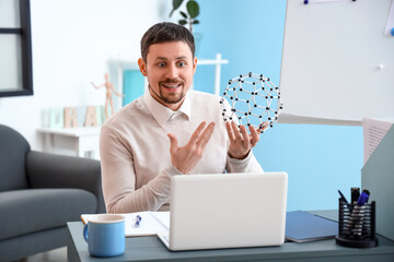 Male tutor with molecular model giving online Physics lesson at home