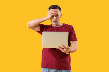 Stressed young man with laptop on yellow background. Deadline concept