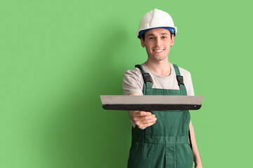 Male worker with putty knife on green background