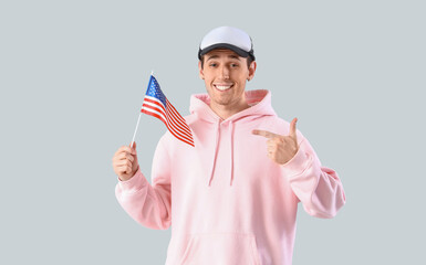 Young man pointing at USA flag on light background