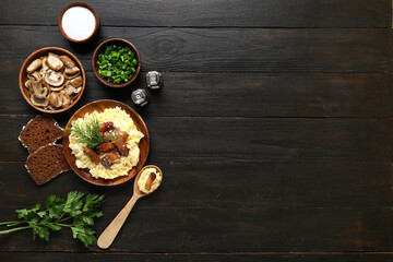 Plate of tasty banosh, spices, mushrooms and bread on black wooden background