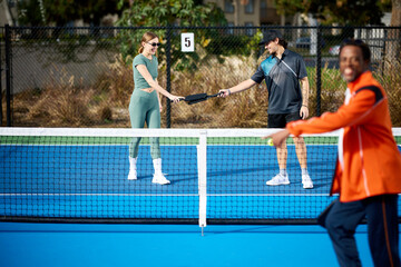 A couple slaps paddles from across a pickleball net