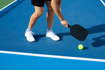 A waist down shot of a pickleball player hitting a ball outside the kitchen