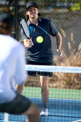 An over the shoulder view of a pickleball player hitting across the net