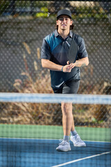 A male pickleball athlete plays a game from across the net