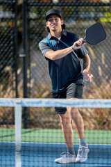 A male pickleball athlete plays a game from across the net