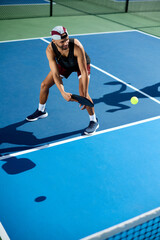 A man in a hat plays pickleball on a blue court
